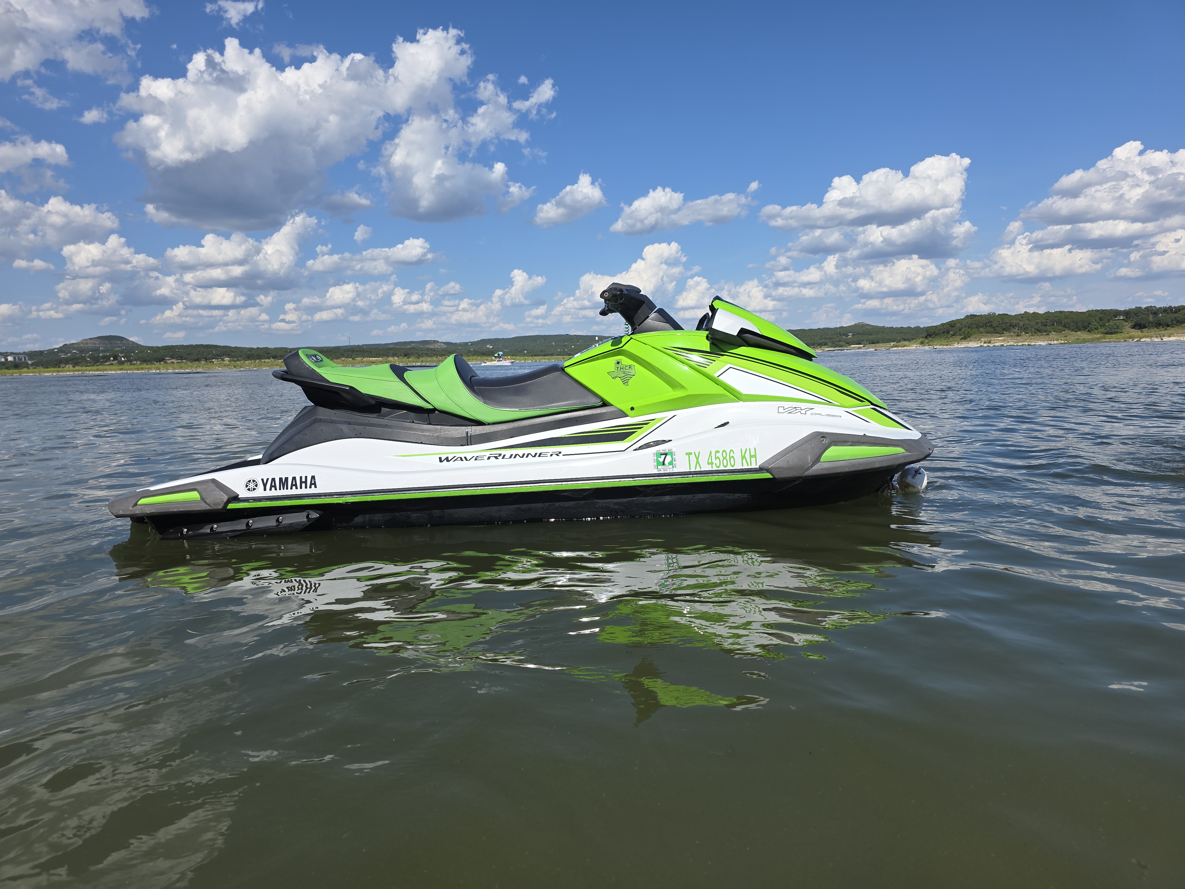 Green and black jet ski floating on Canyon Lake under a bright blue sky