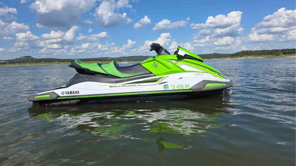 Green and black jet ski floating on Canyon Lake under a bright blue sky
